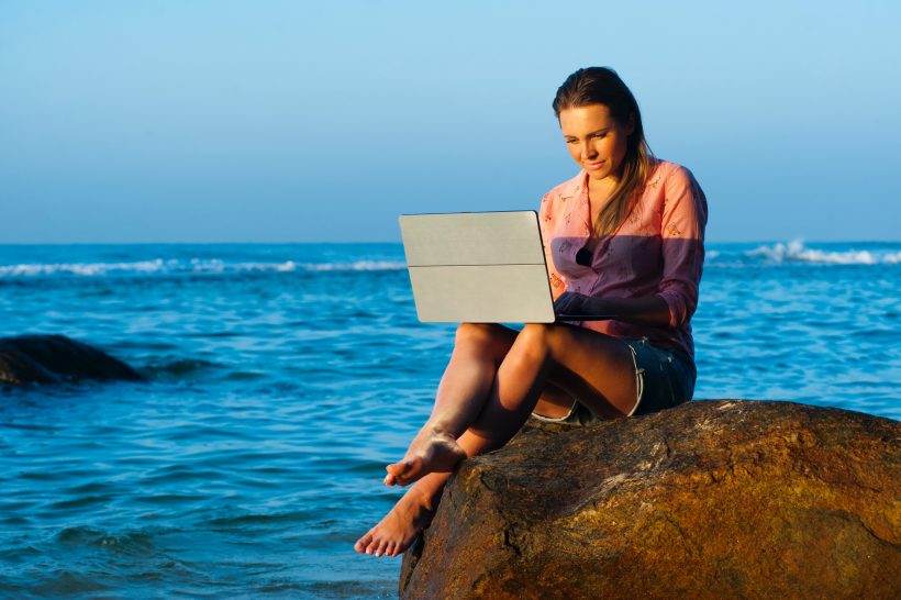 Vállalkozó nő dolgozik a tengerparton